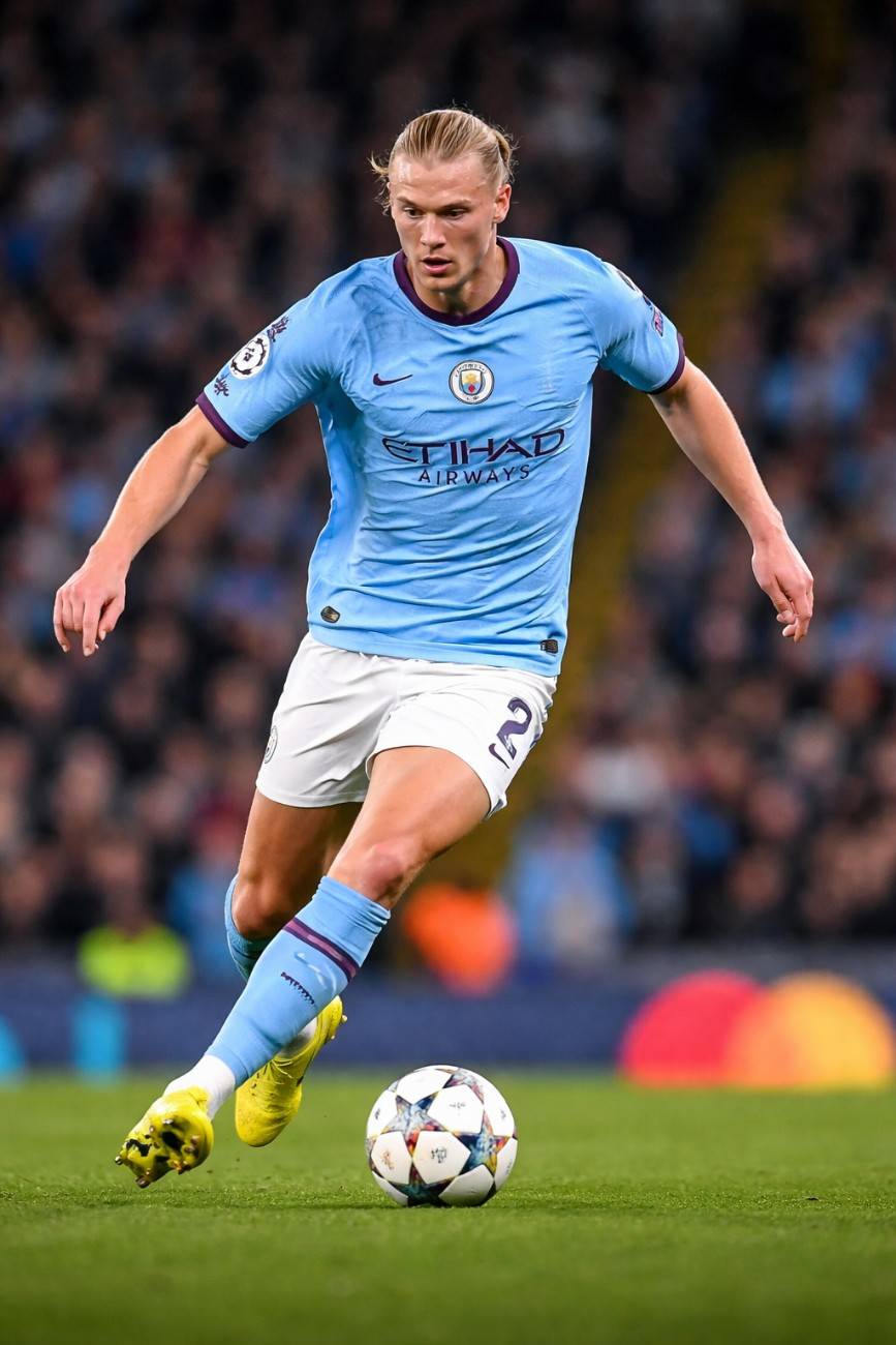 Erling Haaland dribbling the ball during a football match, highlighting his rise to fame and Erling Haaland net worth 2026.